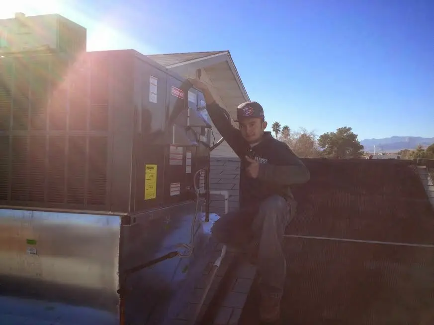 HVAC technician performing AC Tune-Up on a rooftop unit in Kewanee